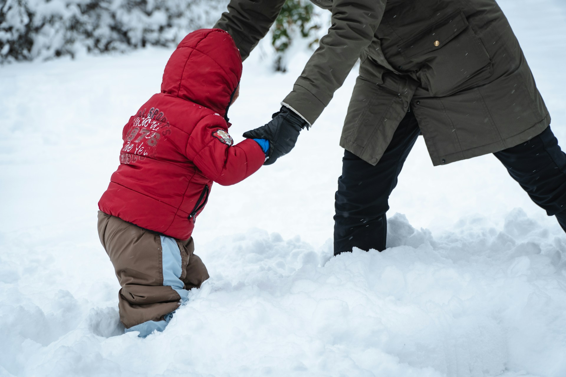 a person holding childs arms in snow