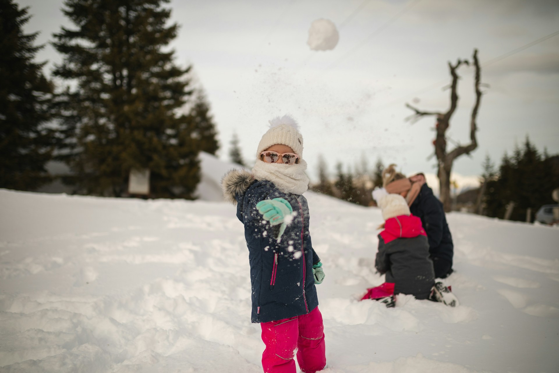girl in pink throwing snowball in winter