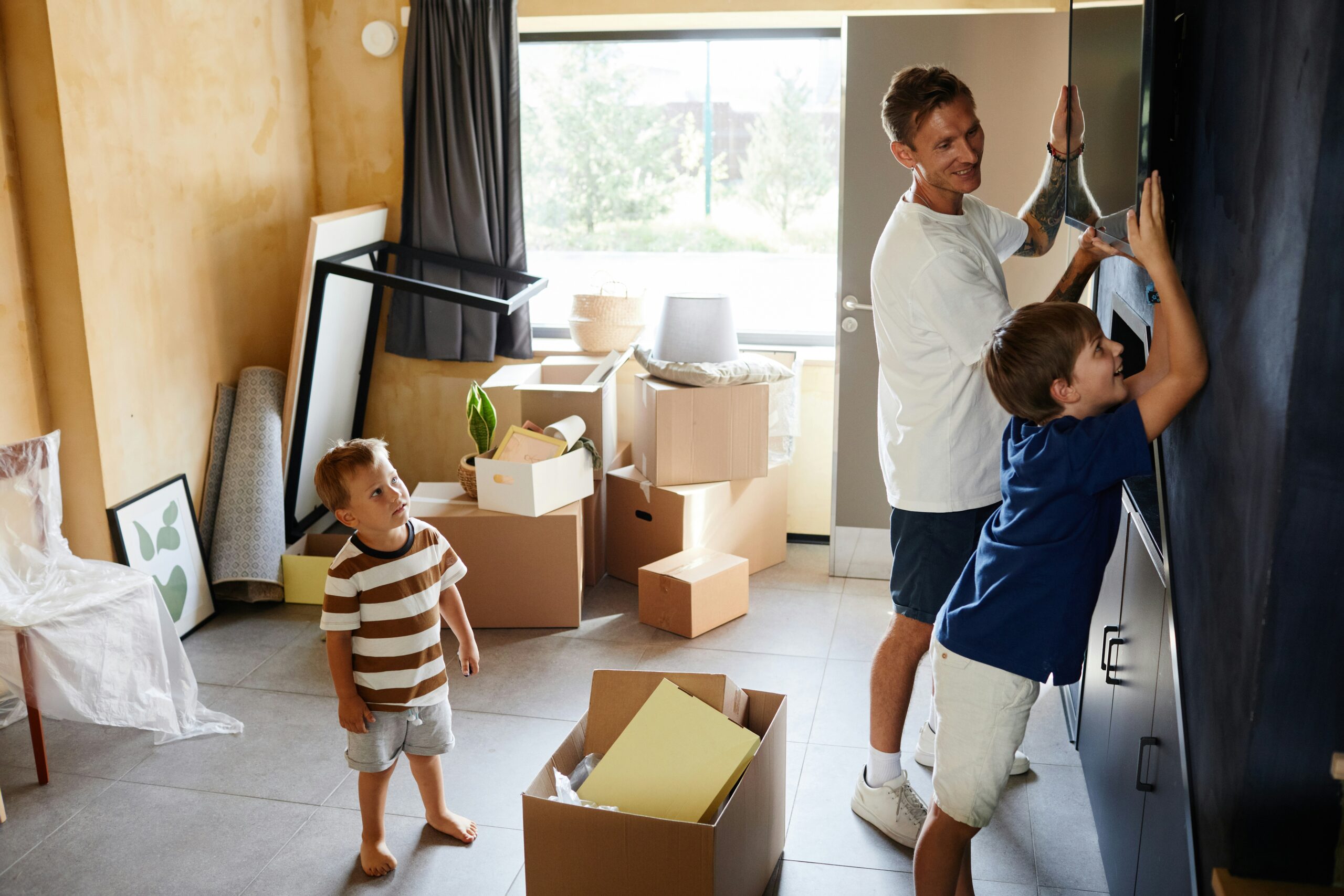 A man and his sons unpacking in their new home, representing the sale of the matrimonial home after a separation or divorce