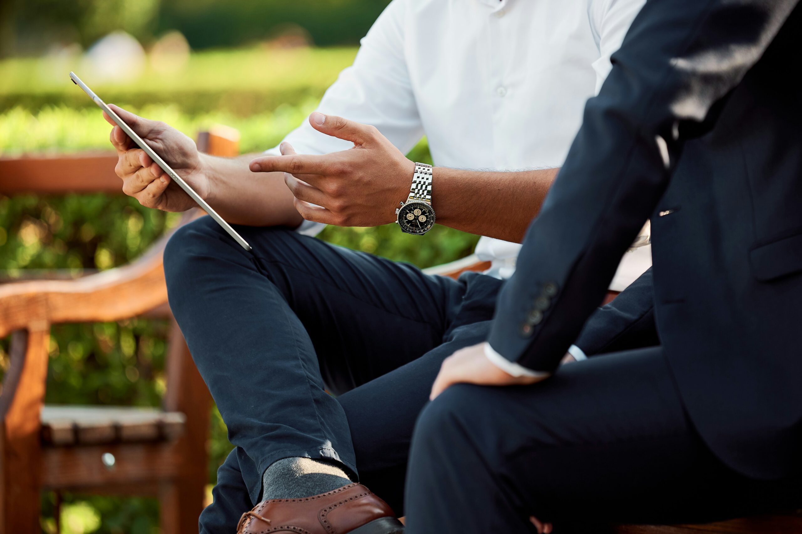 Two businessmen looking at a tablet with one pointing at the tablet's screen, representing the assistance with financial calculations and spousal support matters (alimony) provided by Johnson Miller Family Lawyers in Windsor-Essex.