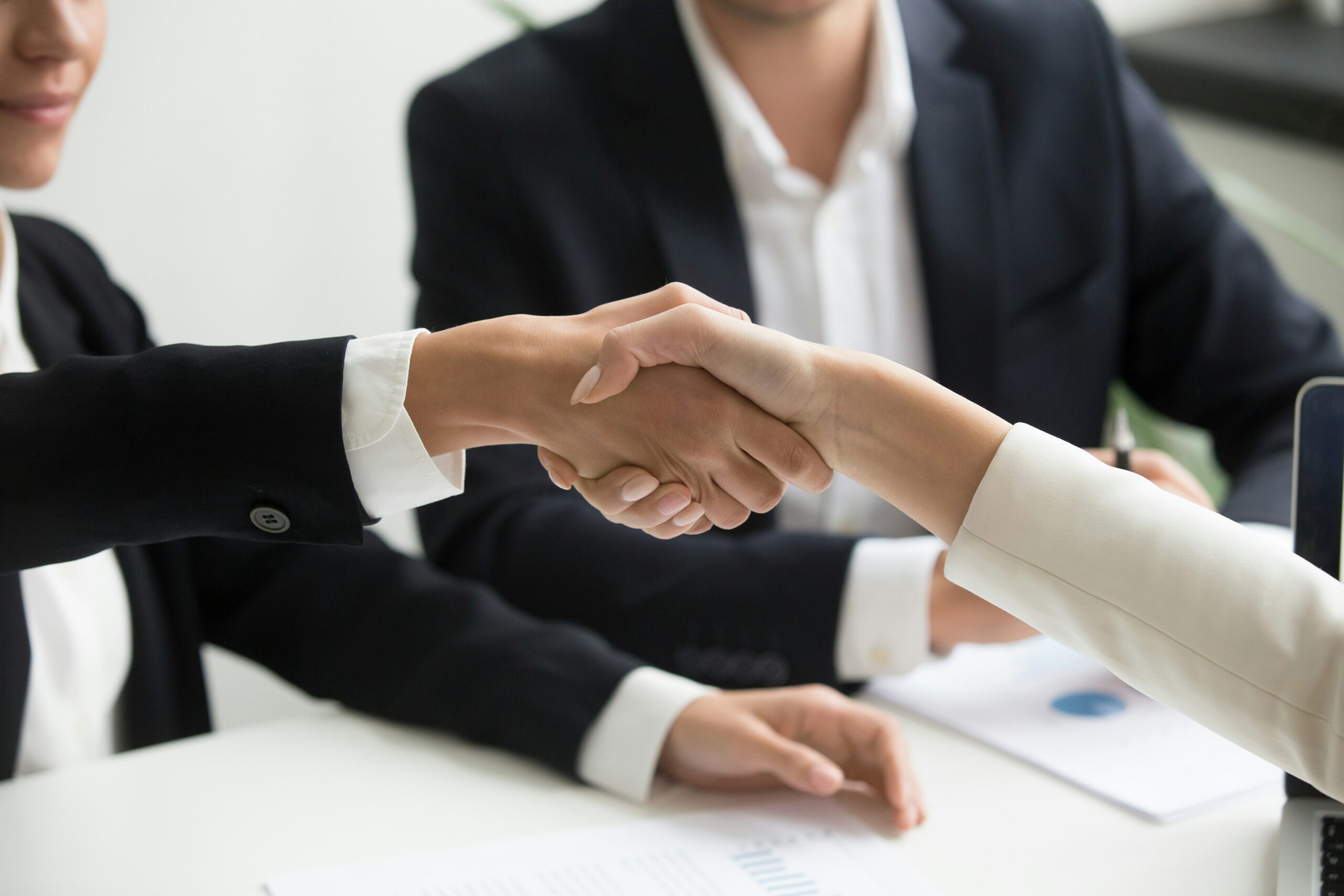 People in suits shaking hands over a desk, representing family law mediation services in separation, divorce, child custody and access, property division, and spousal support, provided by Johnson Miller Family Lawyers in Windsor-Essex.