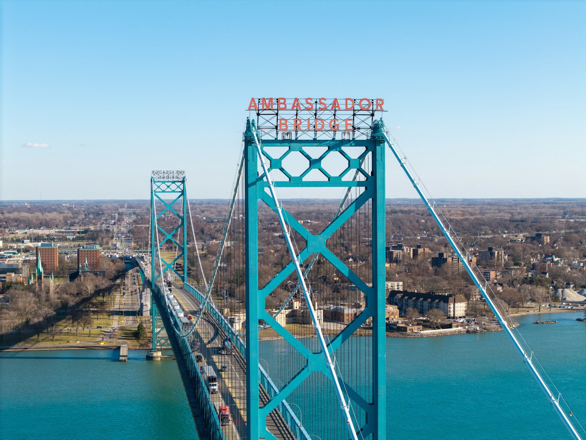 The Ambassador Bridge stretches across the Detroit River and into Michigan under a cloudless blue sky, representing cross-border divorce in Windsor.